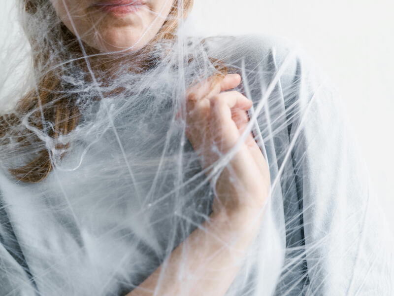Femme prise dans un entrelacs de fils, évoquant un lien qui enserre